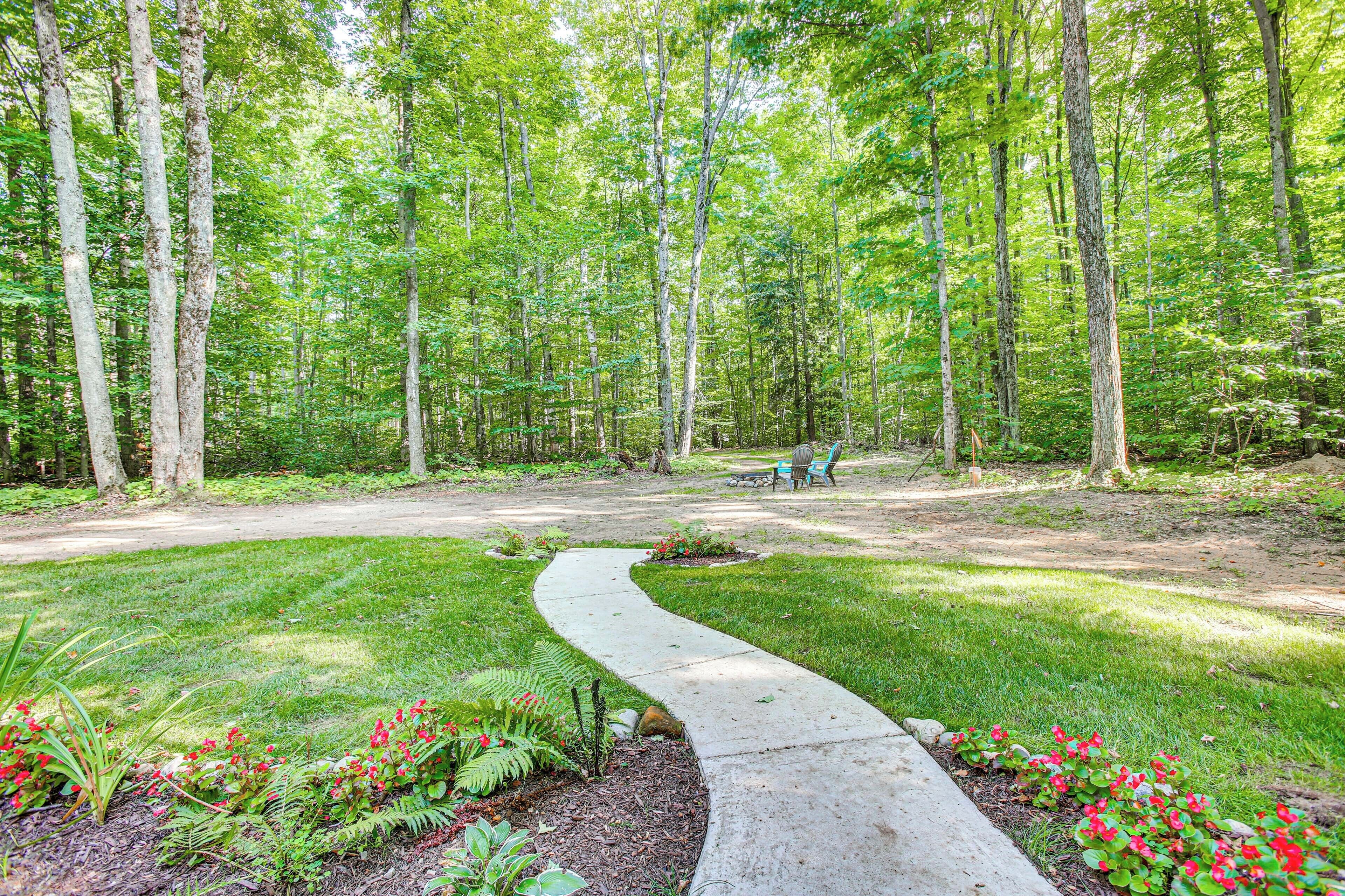 A forested area with a winding pathway, benches, and a picnic table.