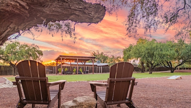 Two Adirondack chairs facing a covered patio with a view of a sunset. - Charming 3BR Villa, Heated Pool and BBQ | Solana 6 (Tucson)