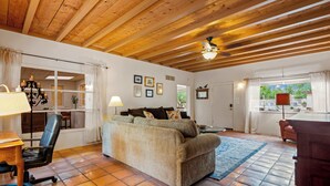 A cozy living room with a sofa, a desk with a chair, a lamp, and a ceiling fan. - Charming 3BR Villa, Heated Pool and BBQ | Solana 6 (Tucson)