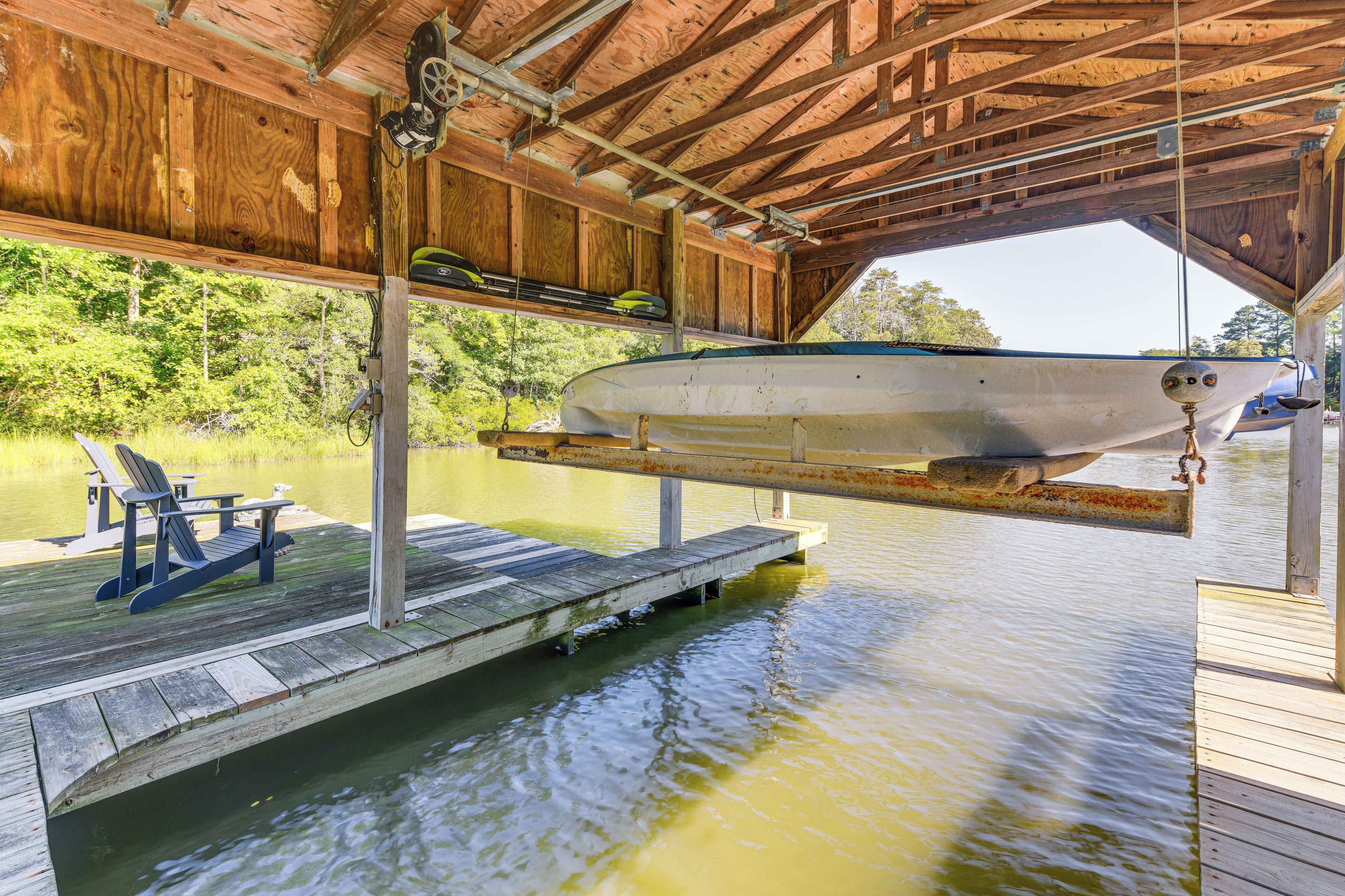 A boat docked under a wooden structure with a dock extending into a body of water.