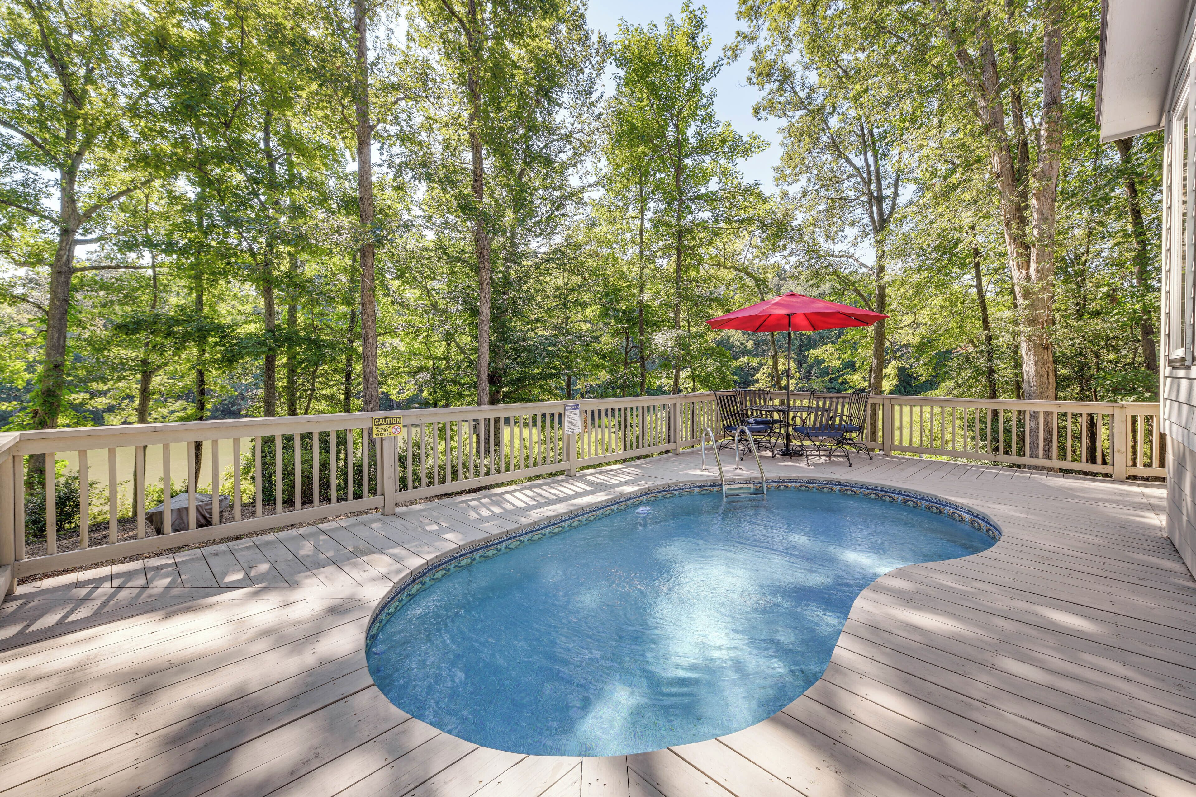 A wooden deck with a swimming pool, surrounded by trees and a wooden railing.