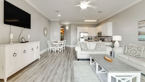 A modern living room with a white sofa, a coffee table, and a dining area with a white table and chairs.