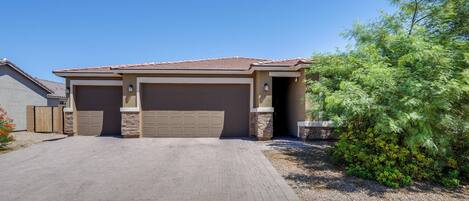 A residential house with a garage, a paved driveway, and a landscaped garden.