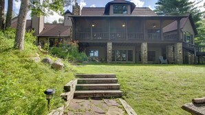 A two-story house with a stone facade, a wooden deck, and a stone staircase leading to the front door. - Sprawling Minnesota Home w/ On-site Lake Access (Nisswa)
