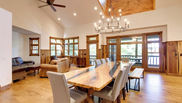 A spacious room with a large wooden dining table, comfortable seating, and large windows allowing natural light. - Sprawling Minnesota Home w/ On-site Lake Access (Nisswa)