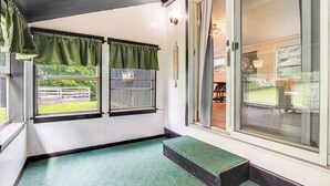 A room with a green carpet, a bench, and a view of a fenced outdoor area. - Peaceful Brookside Getaway ~10 Mi to Okemo Slopes! (Chester)