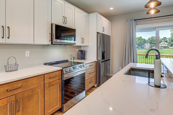 A modern kitchen with white cabinets, stainless steel appliances, and a large island with a sink.