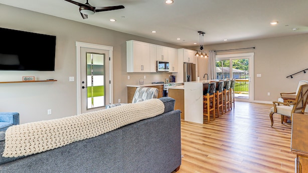 A modern living room with a grey sofa, a flat-screen TV, and a ceiling fan. - Rock Hall Retreat w/ Balcony Near Park & Marina! (Rock Hall)