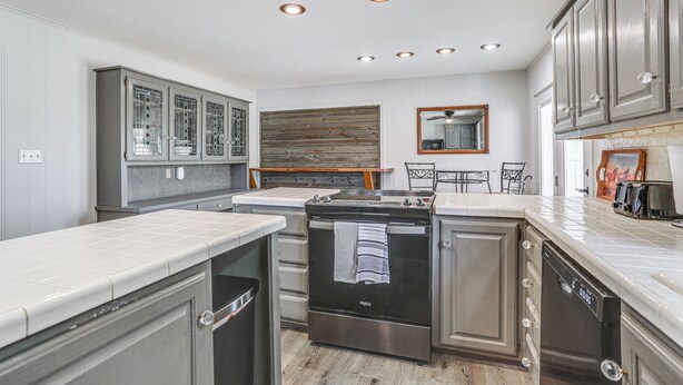 A modern kitchen with stainless steel appliances, white cabinetry, and a wooden accent wall. - Pet Friendly Home w/ Yard & Grill in Crowell! (Crowell)