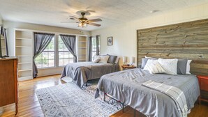 A bedroom with two beds, a ceiling fan, a wooden headboard, and a large window with curtains. - Pet Friendly Home w/ Yard & Grill in Crowell! (Crowell)