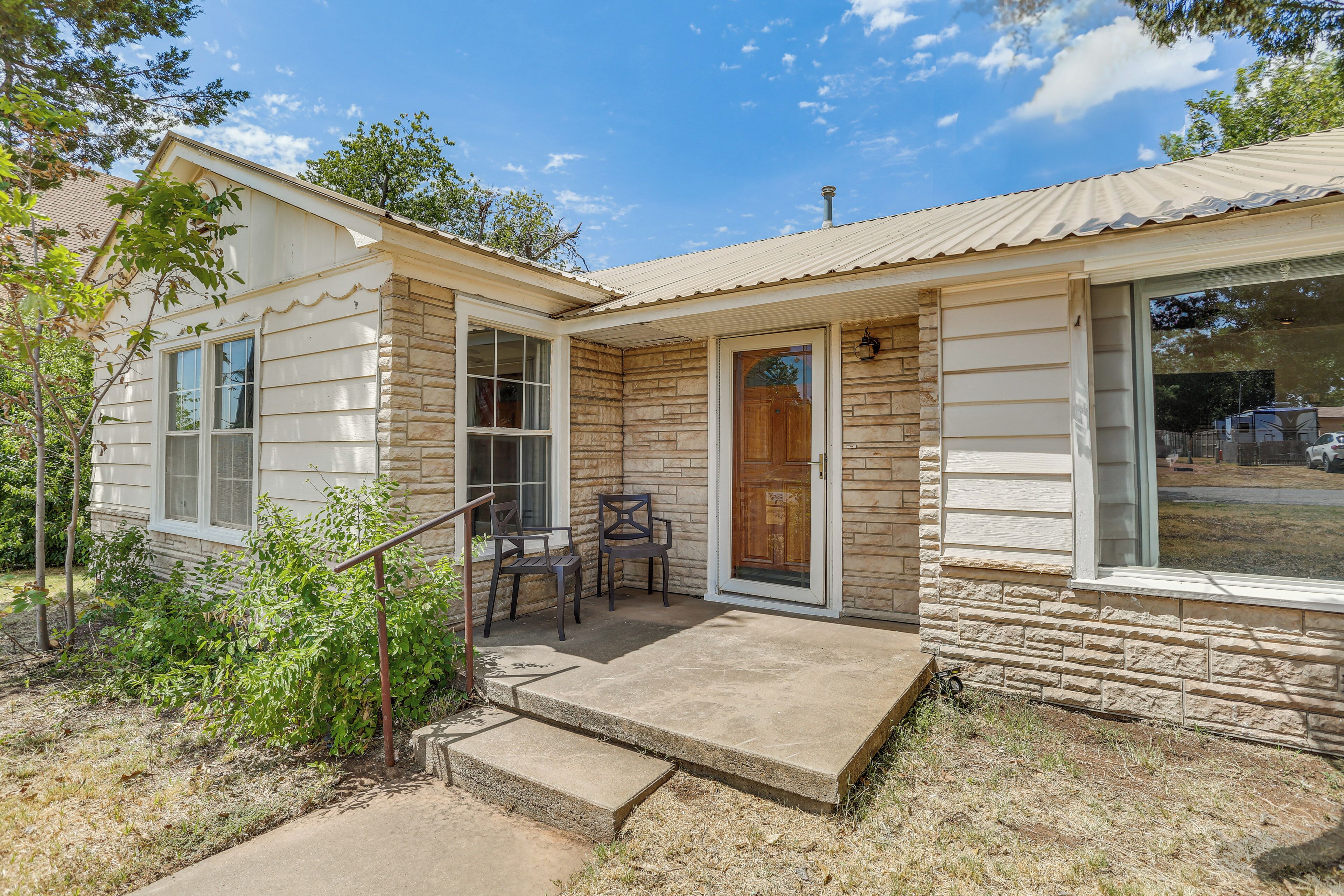 A small, single-story house with a stone exterior and a front porch.