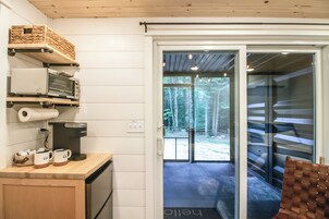 Una cocina con cafetera, microondas y estantes con utensilios de cocina.