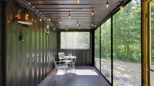 A covered outdoor seating area with a table and chairs, large windows, and string lights. - Nashwauk Studio w/ Ice Fishing on South Fork Lake (Nashwauk)