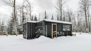 A black cabin in a snowy forest with a door and a bench outside. - Ice Fishing on South Fork Lake: Nashwauk Studio! (Nashwauk)