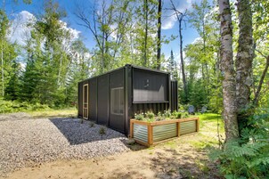 Una cabaña moderna con un ventanal grande, rodeada de un bosque.