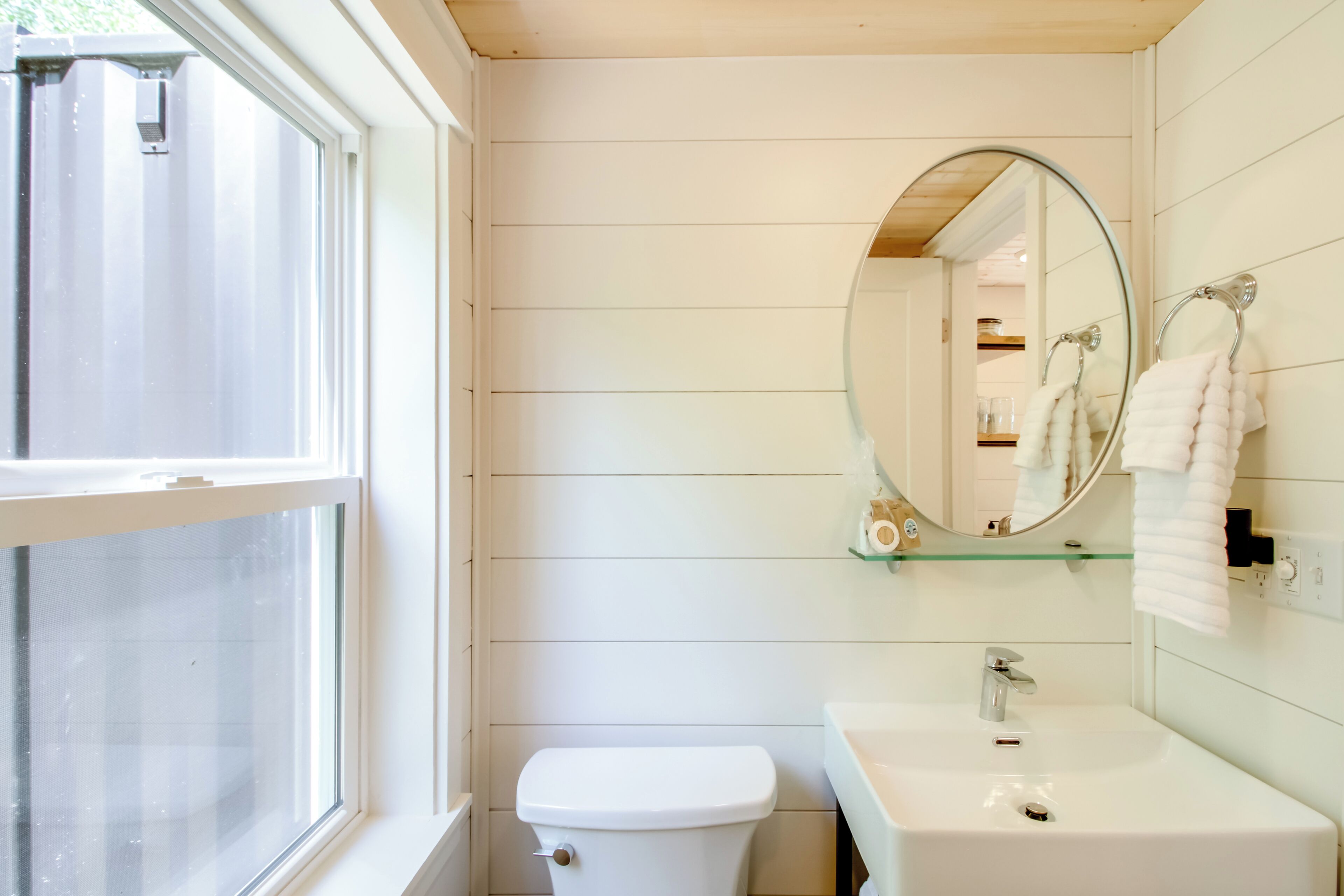 A bathroom with a toilet, sink, and a large mirror.