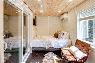 A bedroom with a bed, a bench, a glass door, and a window with blinds.
