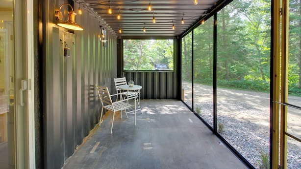 A covered outdoor seating area with a table and chairs, large windows, and string lights. - Ice Fish on South Fork Lake From Nashwauk Studio (Nashwauk)