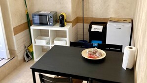 A small kitchen with a table, chairs, a microwave, a coffee maker, and a refrigerator. - San Martino House at the Cathedral (Catania)