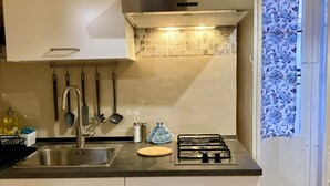A compact kitchen with a stainless steel sink, a gas stove, and a variety of utensils. - San Martino House at the Cathedral (Catania)