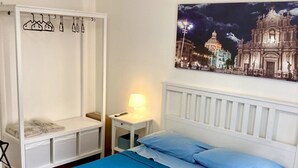 A bedroom with a bed, a wardrobe, a nightstand, and a wall-mounted lamp. - San Martino House at the Cathedral (Catania)