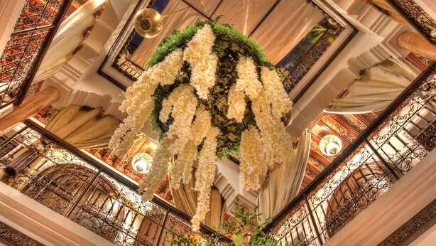 Un intérieur somptueux, agrémenté de balustrades en fer forgé ouvragées, d’un arrangement floral et d’un lustre.