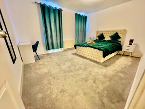 A bedroom with a tufted headboard bed, green curtains, a bedside table, and a chair. - 5bed-10 Guests-near City Centre-free Parking (Leeds)