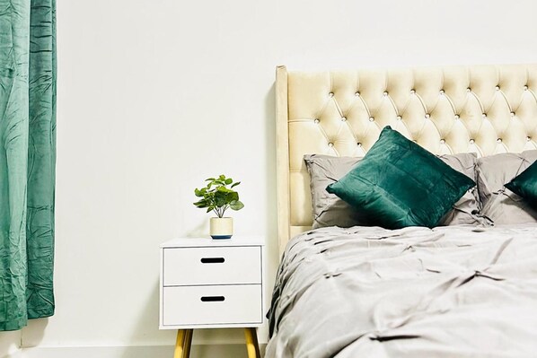 A neatly made bed with a tufted headboard, two pillows, and a bedside table with a plant. - 5bed-10 Guests-near City Centre-free Parking (Leeds)