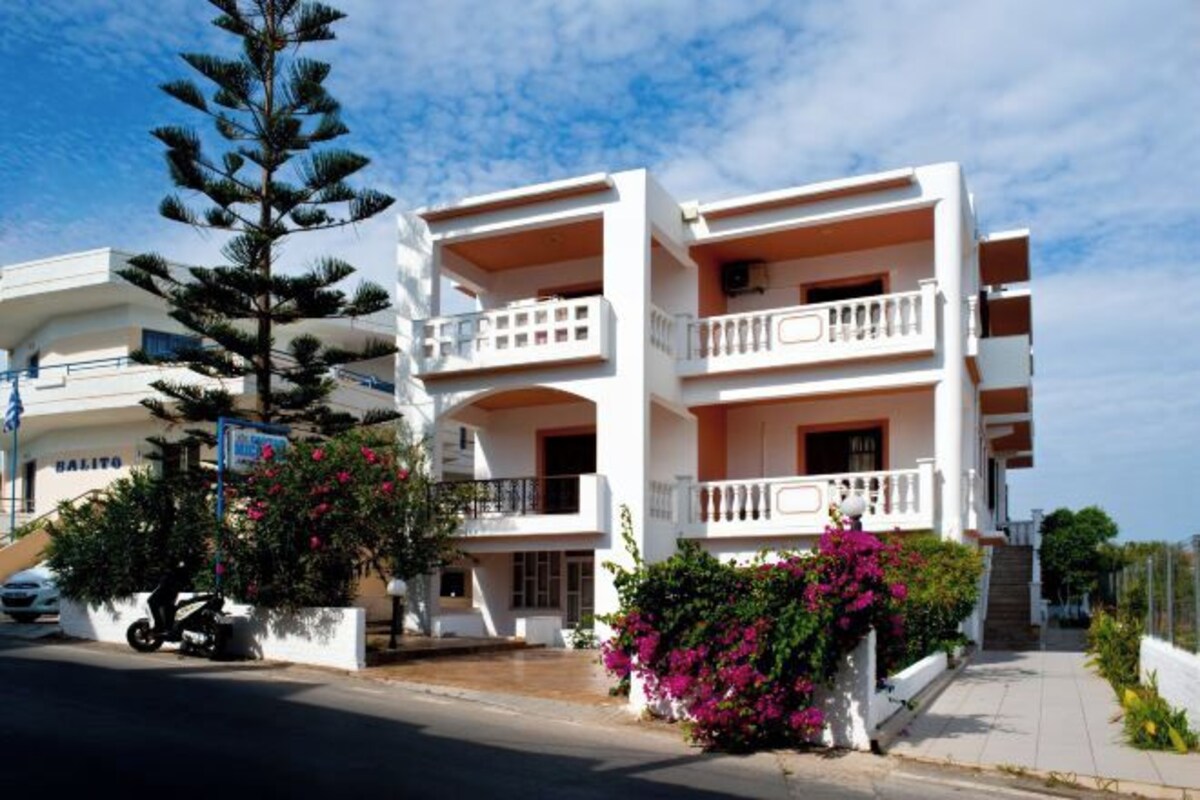 A multi-story building with balconies, a staircase, and a parked motorcycle.