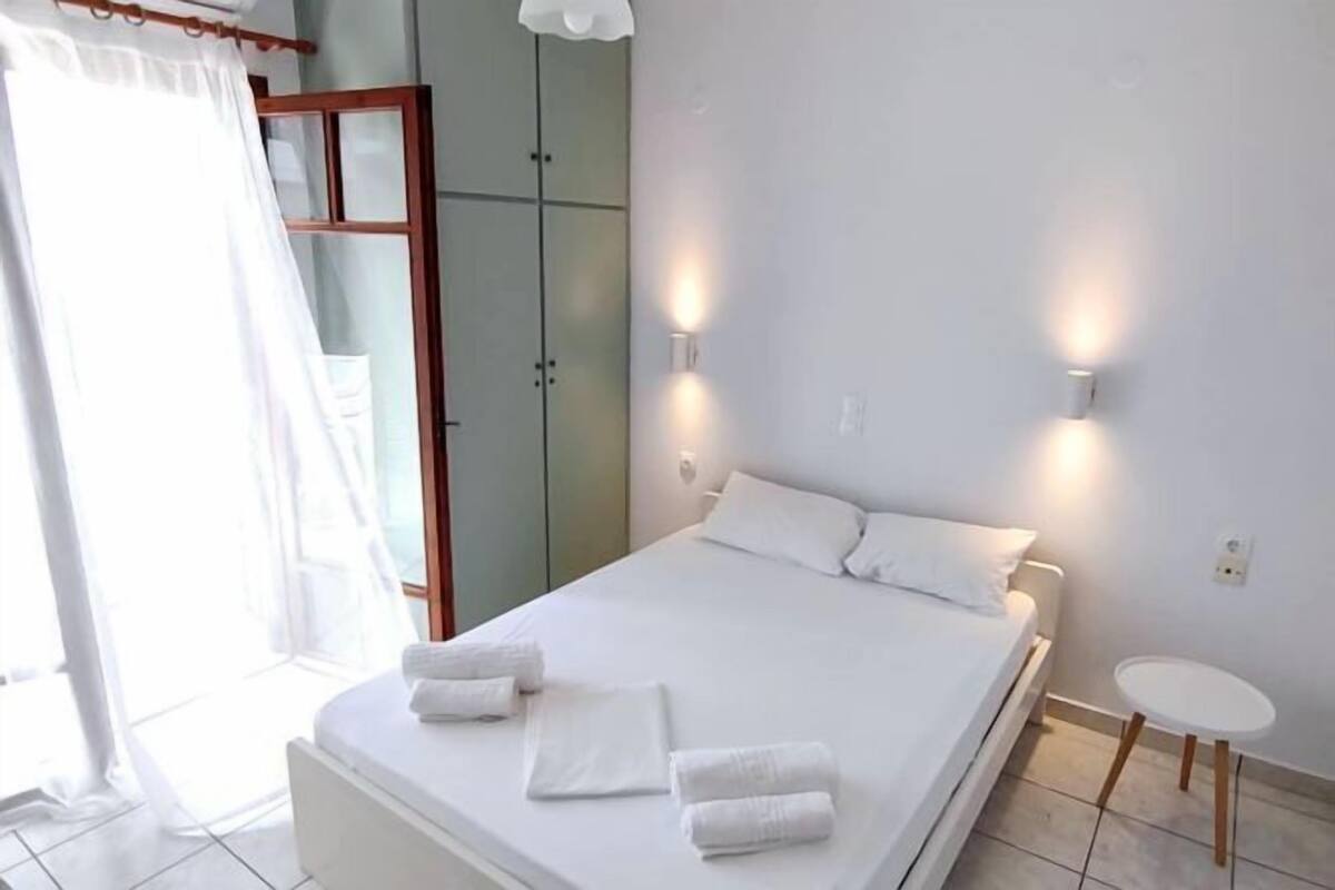 A bedroom with a bed, two wall-mounted lights, a small round table, and a door with a curtain.