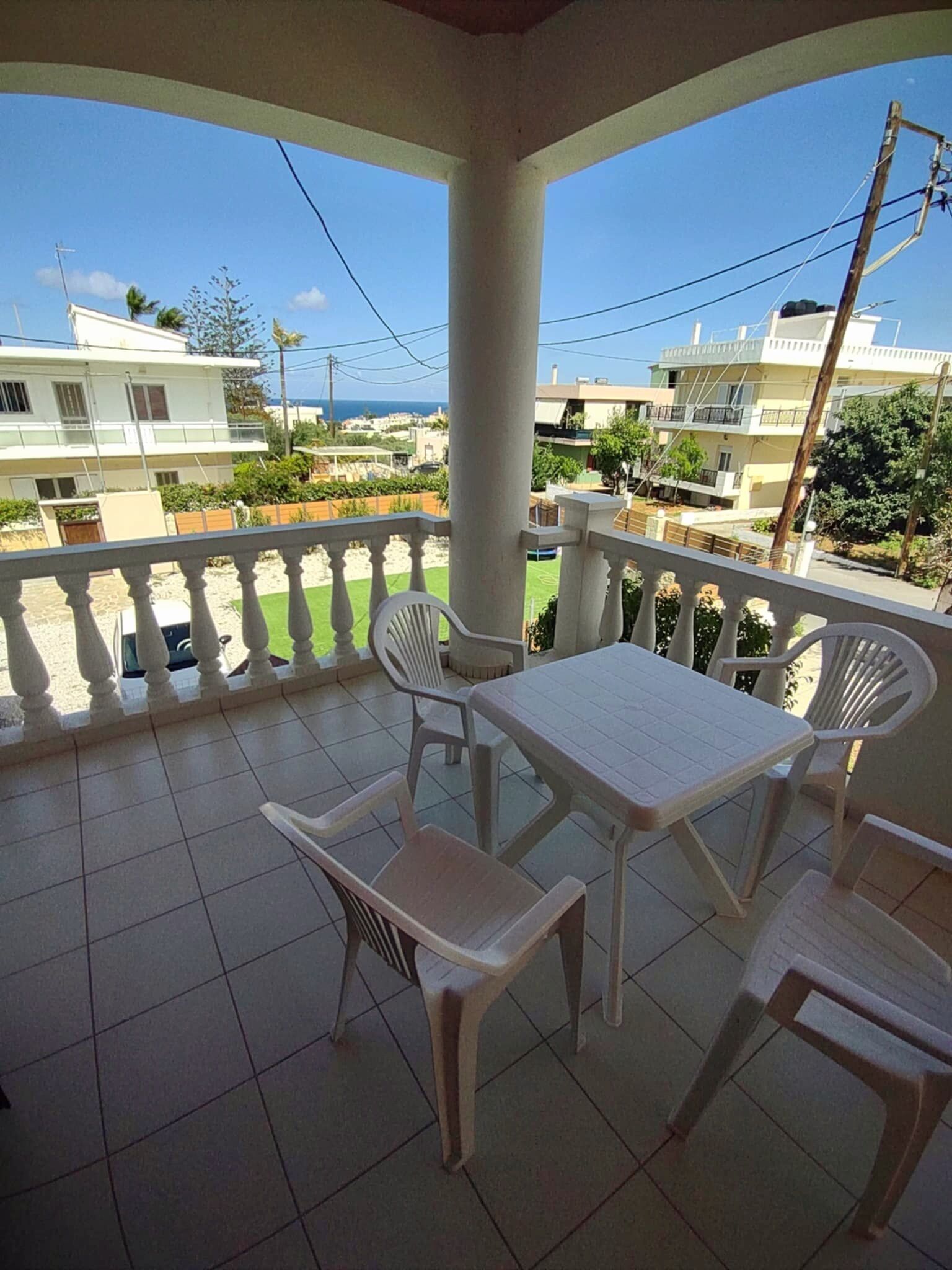 A balcony with a table and chairs, a tiled floor, and a view of surrounding buildings.