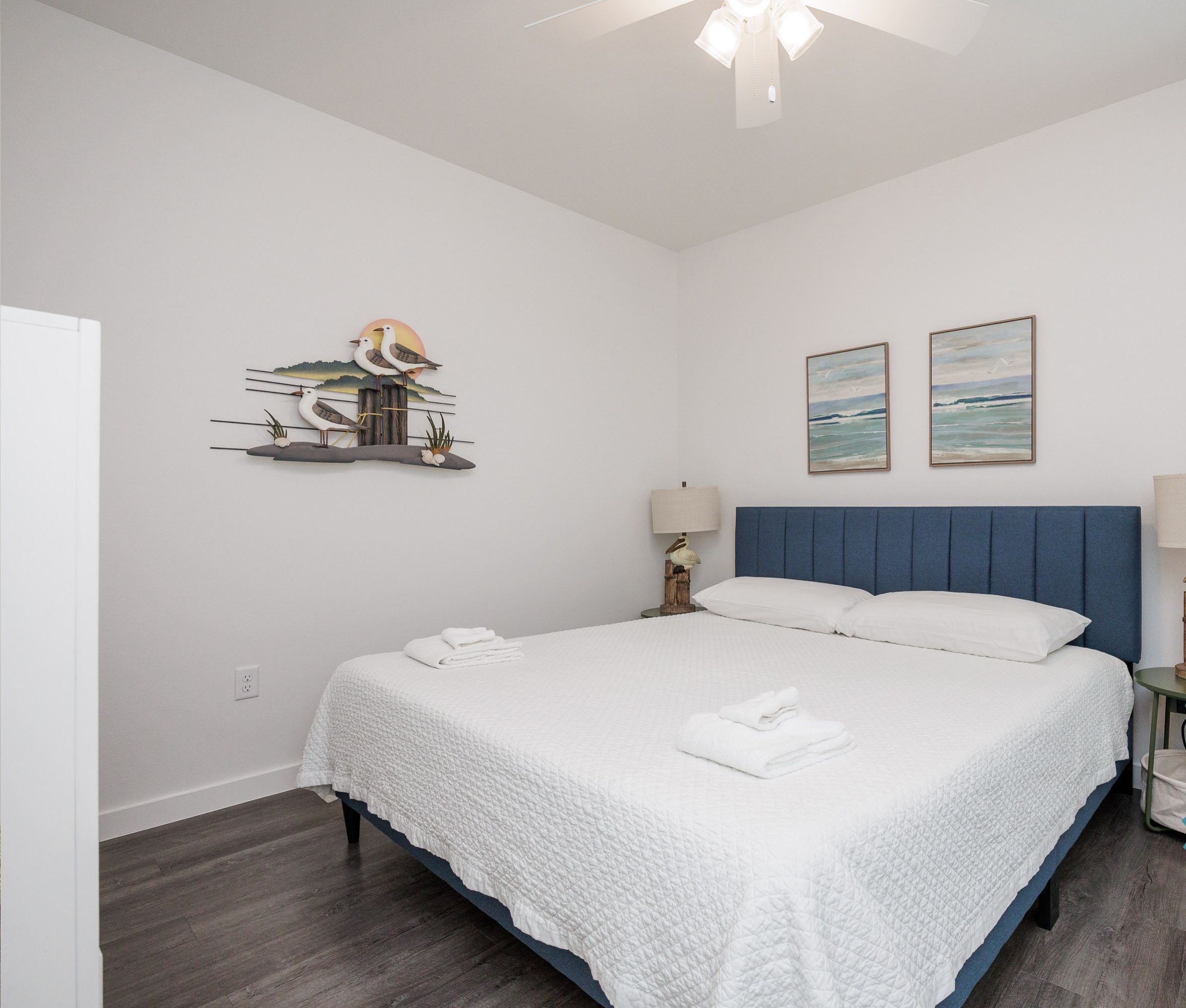 A clean, well-lit bedroom with a bed, two wall-mounted lamps, and a ceiling fan.