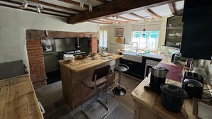 Een rustieke keuken met zichtbare balken, een bakoven en een houten kookeiland met barstoelen.