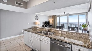 A modern kitchen with granite countertops, a built-in dishwasher, and a large window overlooking the ocean. - Emerald Beach Resort 1133 - Beachfront on the 'Main Strip'! (Panama City Beach)