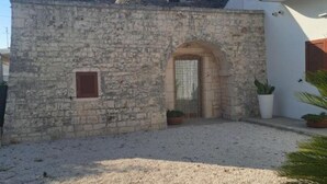 Un bâtiment en pierre avec une entrée rustique, une petite fenêtre et un pot de fleurs.