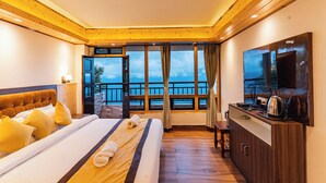 Une chambre d’hôtel avec un grand lit, un plafond en bois, un balcon avec vue, une télévision et une kitchenette.