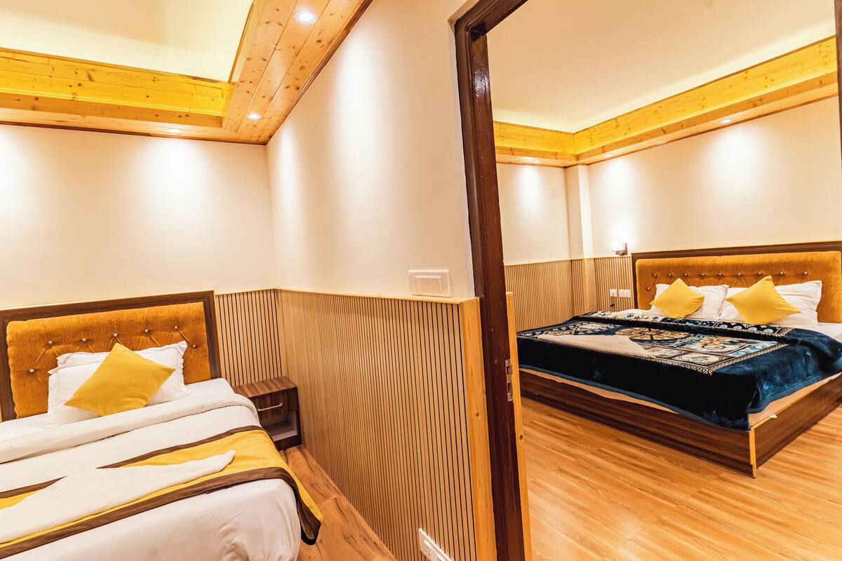 A hotel room with two beds, wooden flooring, and a wooden ceiling.