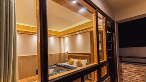 A room with a bed, wooden paneling, and a large mirror. - The Golden Retreat Hotel in Pelling (Gyalshing)