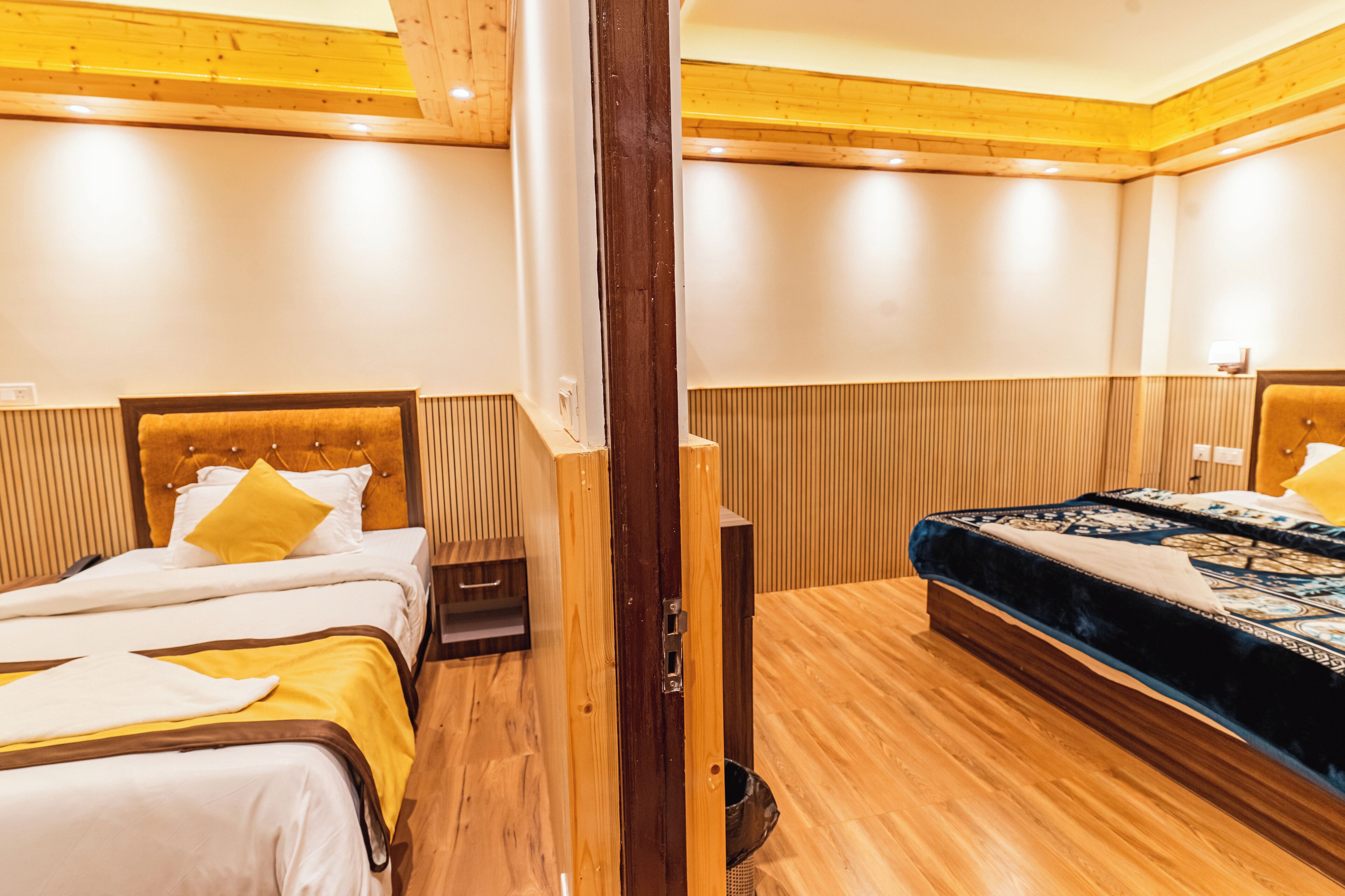 Habitación de hotel con dos camas, suelo de madera y techo de madera.