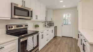 Una cocina moderna con armarios blancos, electrodomésticos de acero inoxidable y piso de madera.