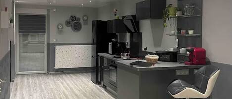 Una cocina moderna con una isla central, taburetes negros y horno empotrado.