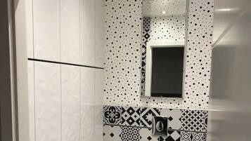 Un baño pequeño con inodoro, espejo y azulejos estampados.
