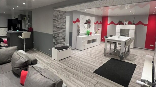 A modern living room with a grey sofa, a black rug, and a dining area with a white table and chairs. - Small house in the country, with terrace!  Pets allowed. (Osne-le-Val)