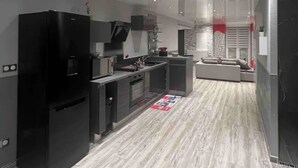 A modern kitchen with black appliances, a central island, and a dining area with a sofa. - Small house in the country, with terrace!  Pets allowed. (Osne-le-Val)