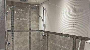 A modern shower with a glass door, tiled walls, and a wooden floor.