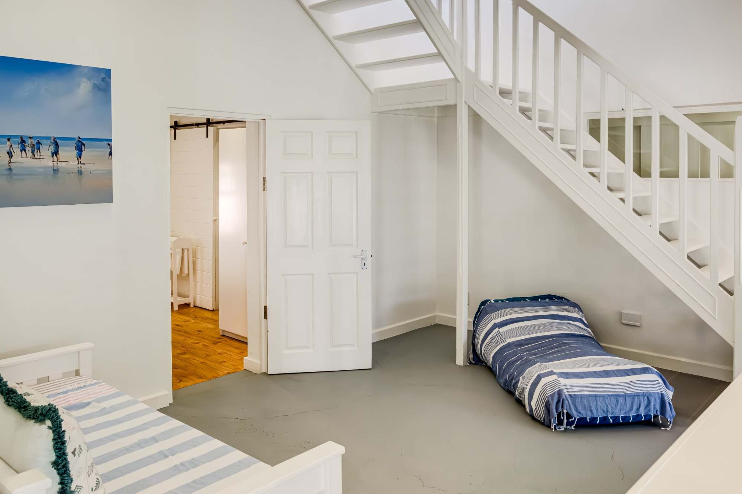 A room with a bed, a staircase, and a door leading to a bathroom.
