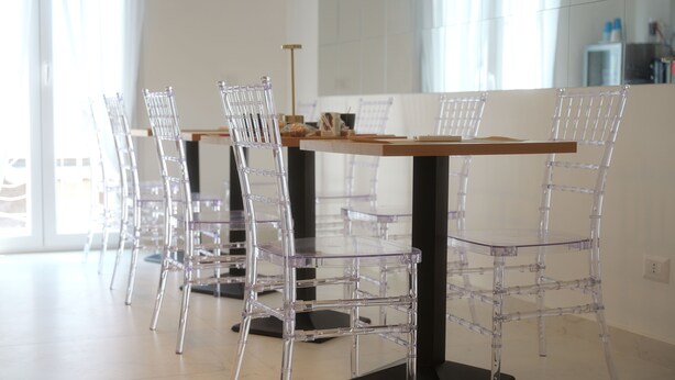 A modern dining area with clear plastic chairs and a wooden table. - Il Vicoletto B&B in centro (Ciro Marina)