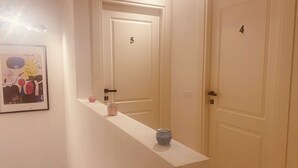 A hallway with two doors, numbered 4 and 5, and a white console table with a vase and a candle. - Il Vicoletto B&B in centro (Ciro Marina)