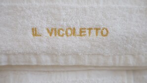 A white towel with the text "IL VICOLETTO" embroidered in gold. - Il Vicoletto B&B in centro (Ciro Marina)