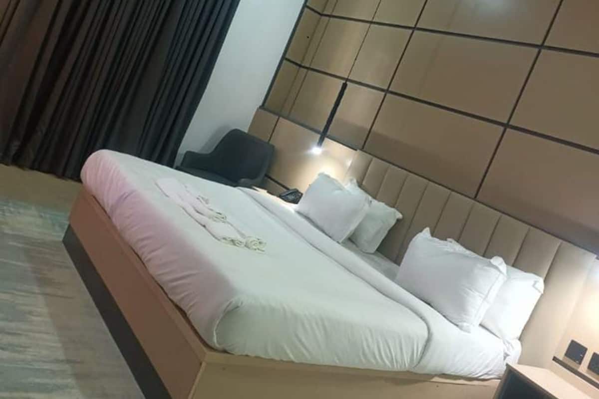 Une chambre d’hôtel avec un grand lit, un bureau, une chaise et un rideau.